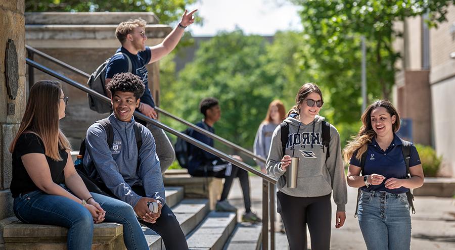 Happy UA students walking out of and in front of Buchtel Hall on The University of Akron campus.